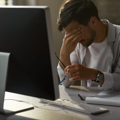 Exhausted businessman holding his head in pain while working on