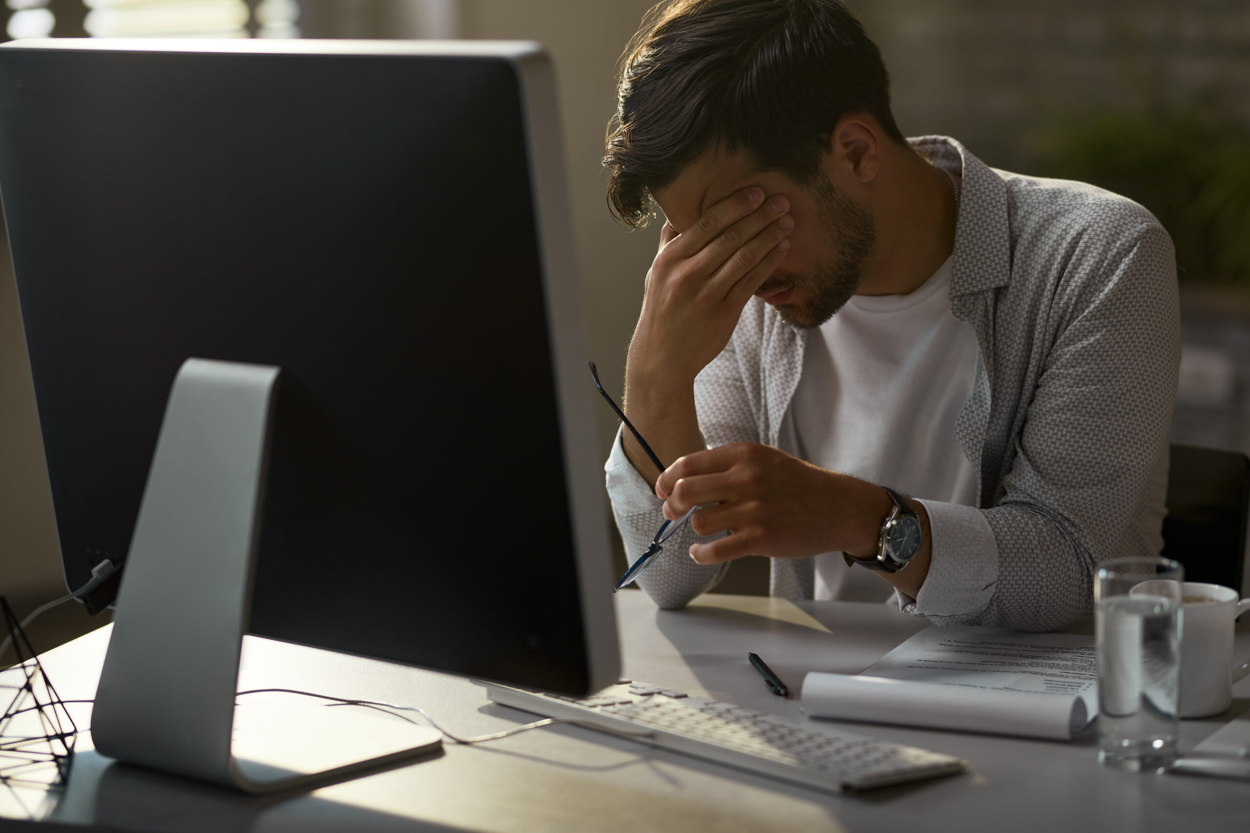 Exhausted businessman holding his head in pain while working on